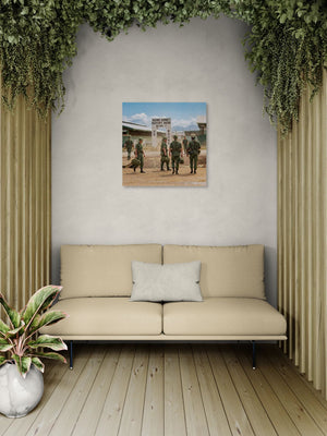 Beige sofa in a room with a wall painting of soldiers and plants.