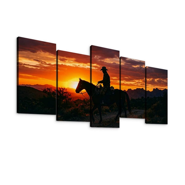 Five-panel canvas wall art showing a cowboy riding a horse across a desert landscape at sunset, with dramatic orange and red sky tones and dark silhouetted foreground.