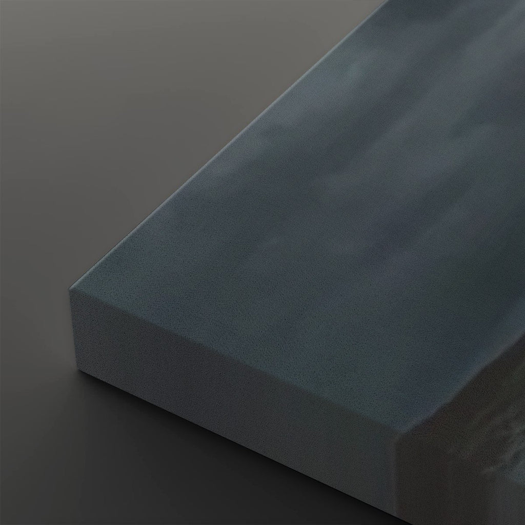 A close-up of a rectangular block of matte dark blue-gray material, showing its textured surface and angled edges against a dark gray background.