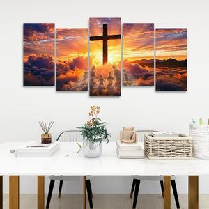 A five-panel canvas wall art set depicting a dramatic sunset sky with a large cross and silhouetted figures, displayed above a white dining table in a modern room setting.