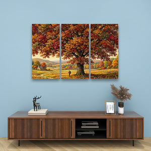 A three-panel canvas wall art set depicting a large autumn tree with red, orange, and yellow foliage over a scenic landscape, displayed on a light blue wall above a wooden console table.