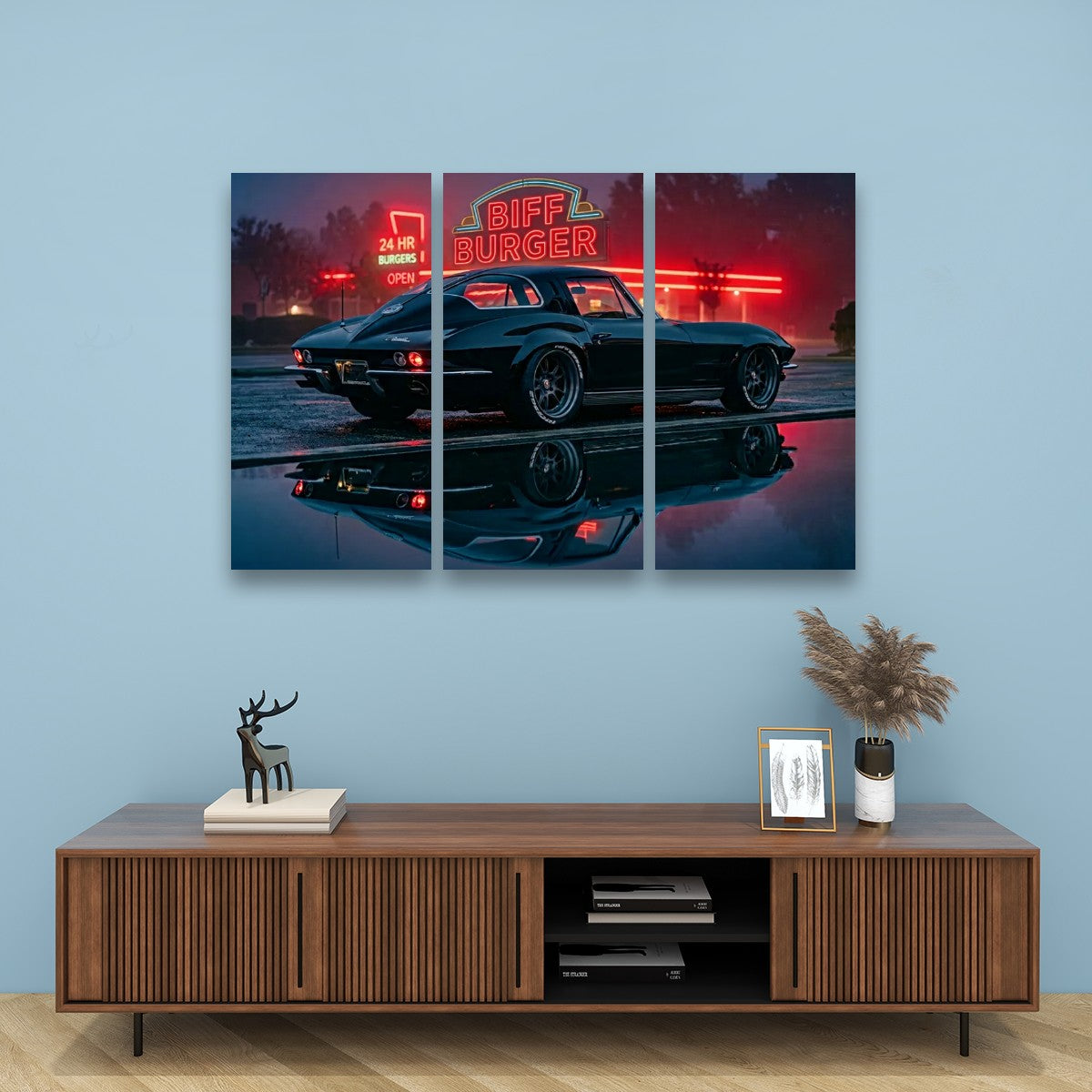 A three-panel canvas wall art print depicting a classic 1963 Split Window Chevy Corvette car at night with a glowing red 'Biff Burger' neon sign, displayed on a light blue wall above a wooden console table with decorative items.