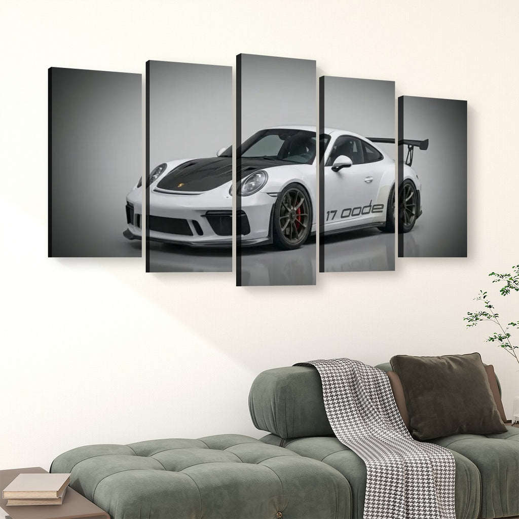 A 5-panel canvas wall art set depicting a white Porsche 911 'Code 17' sports car, displayed in a modern living room setting above a green tufted sofa.
