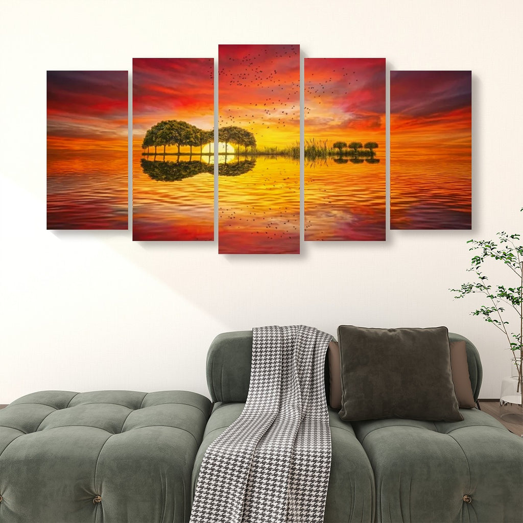 A 5-panel canvas wall art set depicting a vibrant sunset over water with a guitar-shaped island and its reflection, displayed above a green sofa in a living room setting.