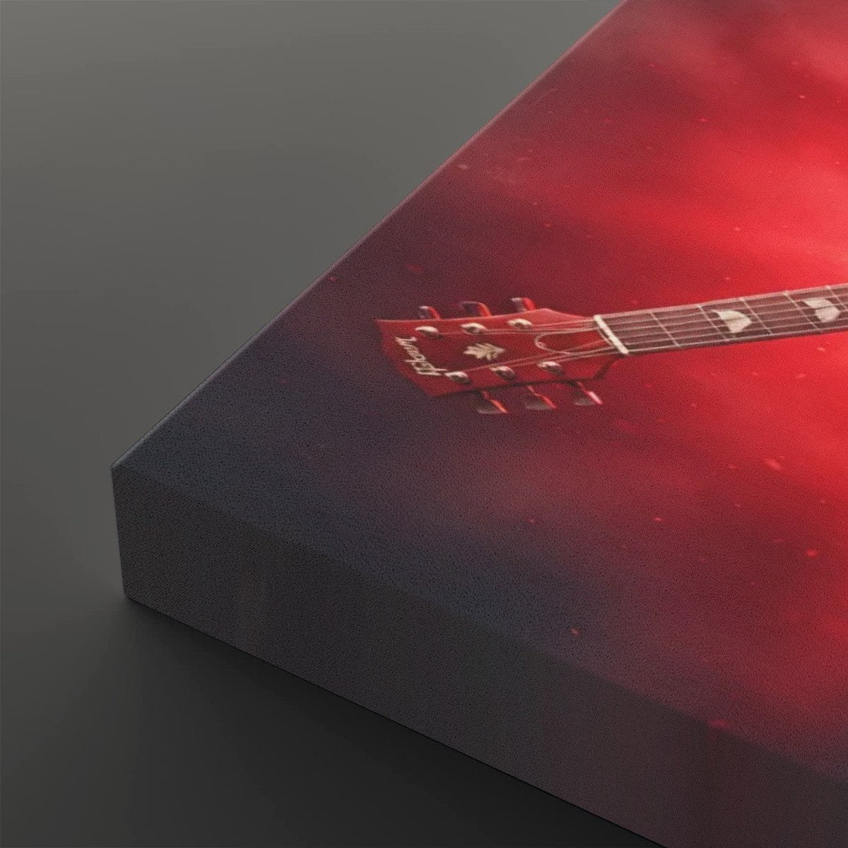 A close-up of a rectangular canvas or print showing a red acoustic guitar headstock and neck against a smoky red and dark gray background, photographed on a dark gray surface.