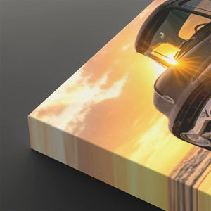 A close-up of a rectangular canvas or print showing a dramatic sunset sky with bright yellow and orange light, alongside part of a dark car. The print is photographed at an angle on a dark gray background.