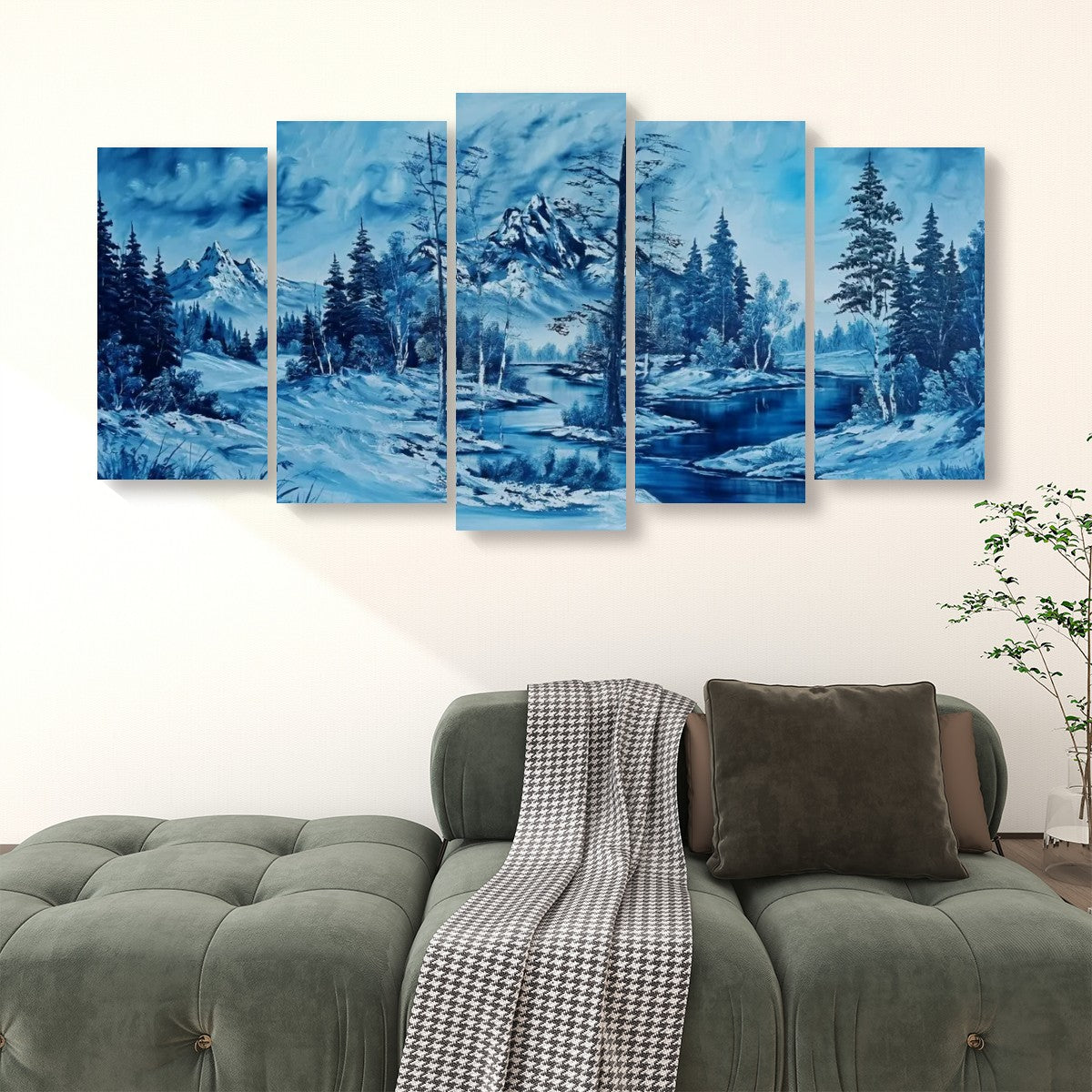 A five-panel canvas wall art set depicting a blue-toned snowy mountain landscape with pine trees and a river, displayed above a green sofa in a living room setting.