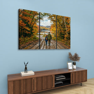 A three-panel canvas wall art print depicting a father and child walking down a forest path in autumn, displayed on a light blue wall above a wooden console table with decorative items.