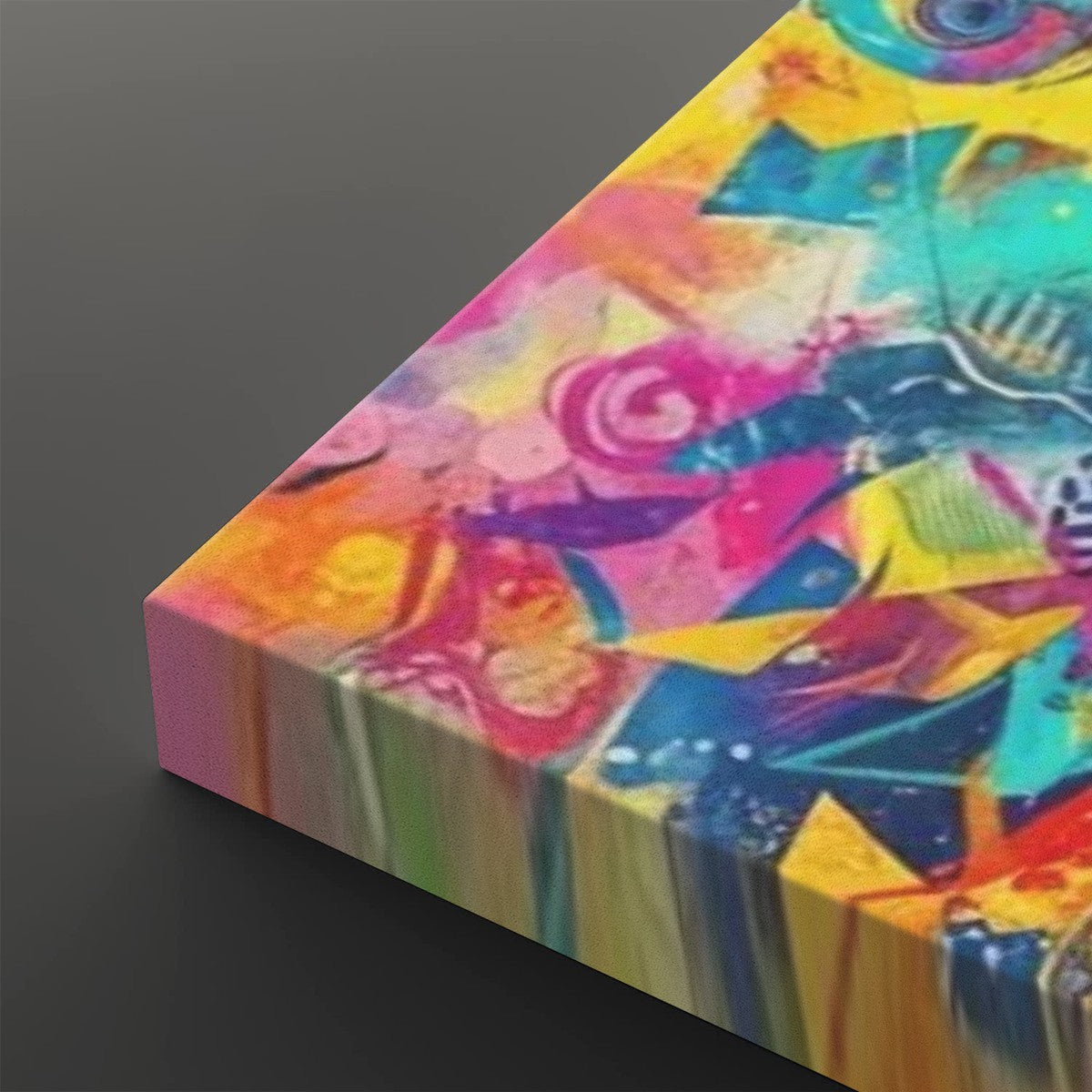 A rectangular canvas print featuring a vibrant, multicolored abstract painting with splashes of pink, yellow, blue, green, and orange, shown at an angle on a dark gray background.
