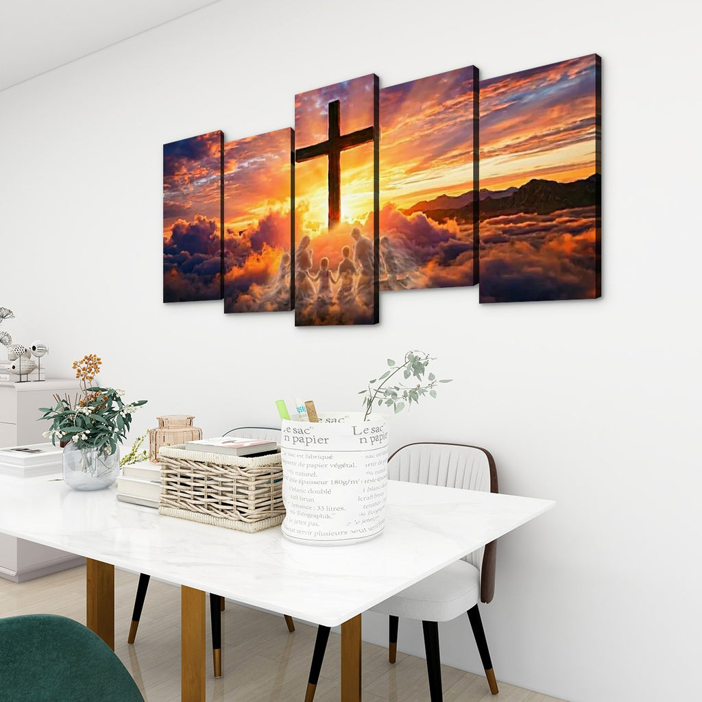 A 5-panel canvas wall art set depicting a dramatic sunset sky with a large cross silhouette, displayed on a white wall above a dining table in a modern room setting.