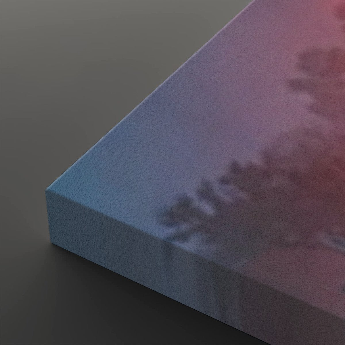 A close-up of a rectangular canvas or panel with a soft gradient surface shifting from light blue to pink and purple, with a blurred tree-like shadow printed across it. The product is shown at an angle on a dark gray background.
