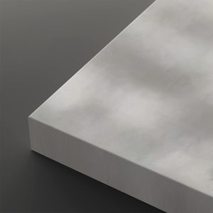 A close-up of a light gray rectangular panel or board shown at an angle against a dark gray background.