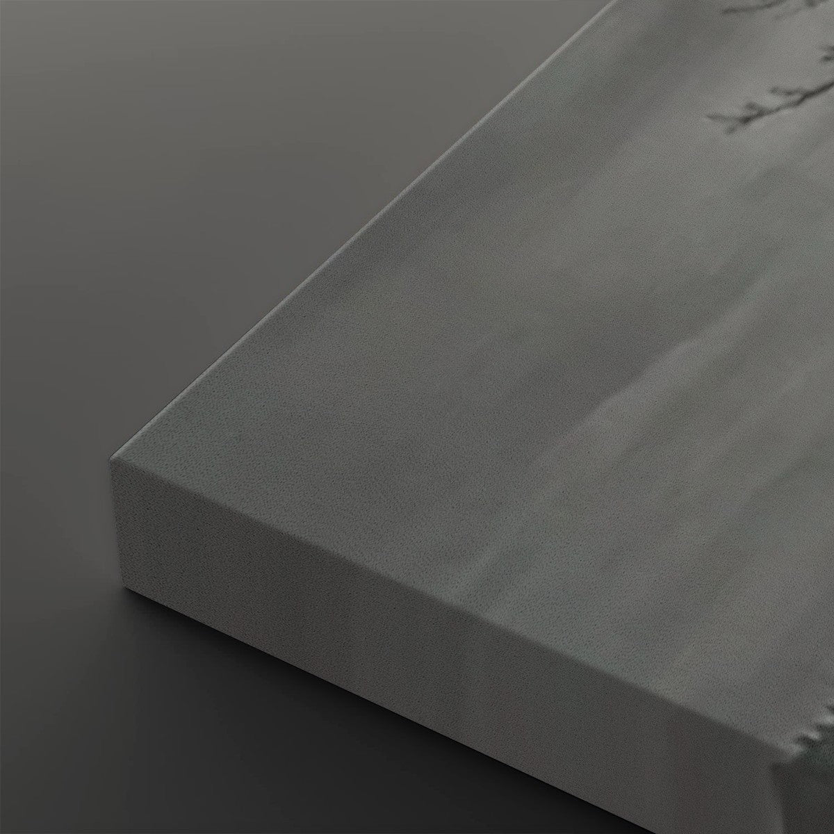 A close-up of a gray textured canvas or panel with a visible wrapped edge, photographed on a dark gray background.