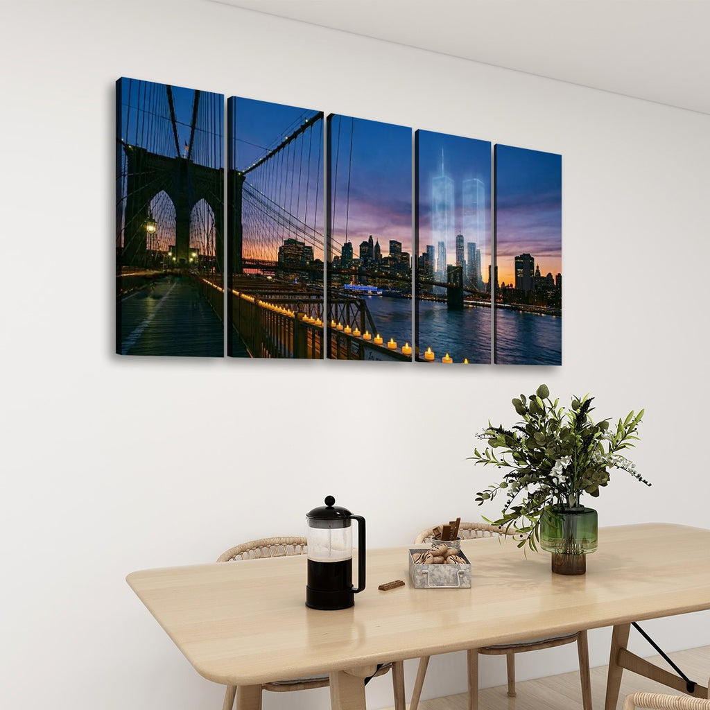 A five-panel canvas wall art set depicting the Brooklyn Bridge and New York City skyline at dusk, displayed on a white wall above a light wood dining table with chairs, a coffee press, and a plant.