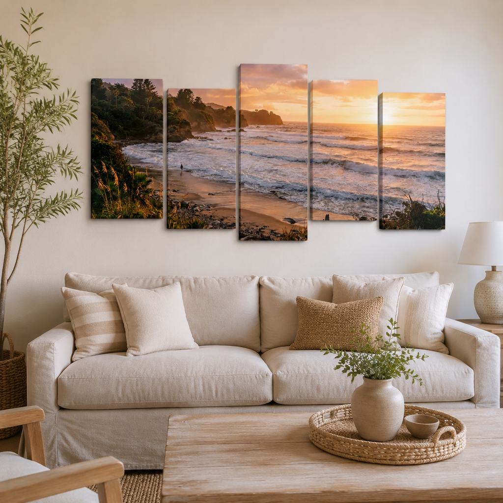 A five-panel canvas wall art set depicting a coastal sunset beach scene, displayed above a beige sofa in a modern, neutral-toned living room.