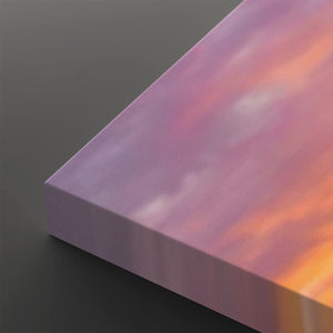 A close-up of a rectangular canvas or panel with a pastel sunset sky design, showing pink, purple, and orange tones, photographed on a dark gray background.