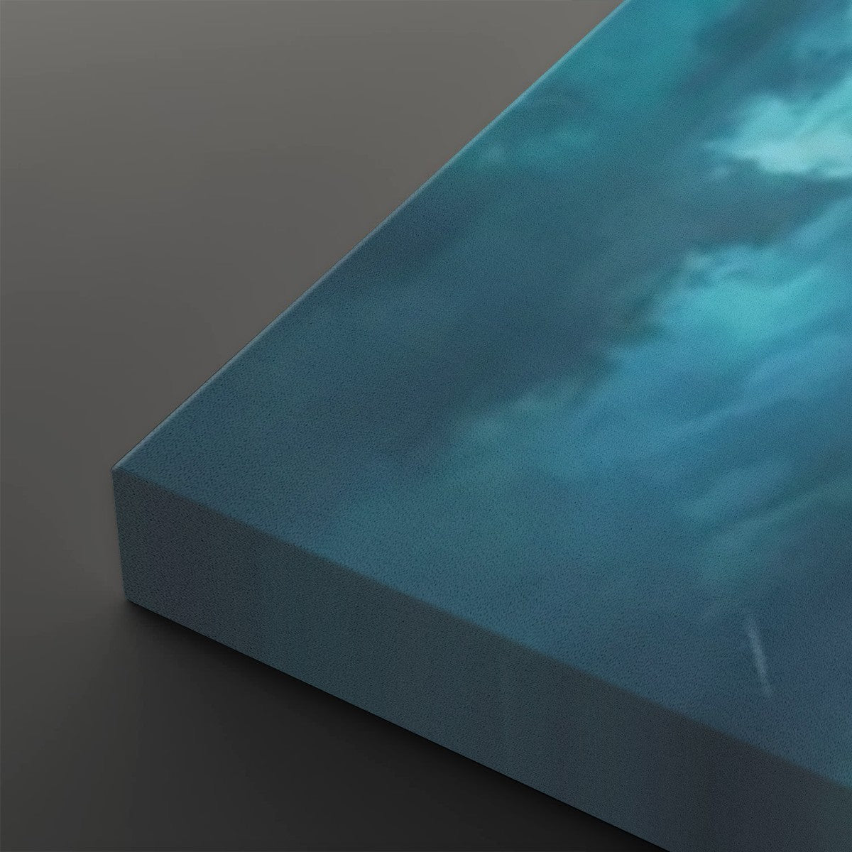 A close-up of a square canvas print showing its wrapped edge, featuring a textured blue and teal sky with soft white clouds on a dark gray background.