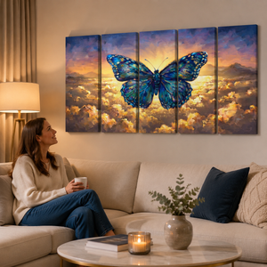 A five-panel canvas wall art set depicting a large blue butterfly over a glowing sunset sky and clouds, displayed above a beige sofa in a warmly lit living room with a woman sitting on the couch.