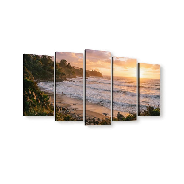 A five-panel split canvas wall art print depicting a coastal beach at sunset, with ocean waves, sandy shore, cliffs, and warm golden sky, shown against a plain white background.