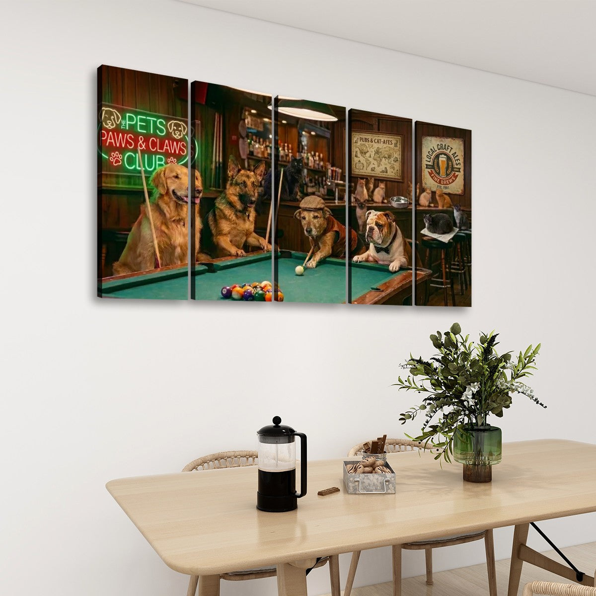 A multi-panel canvas wall art set depicting dogs playing pool in a bar scene, displayed on a white wall above a dining table with chairs, a French press, and a potted plant.