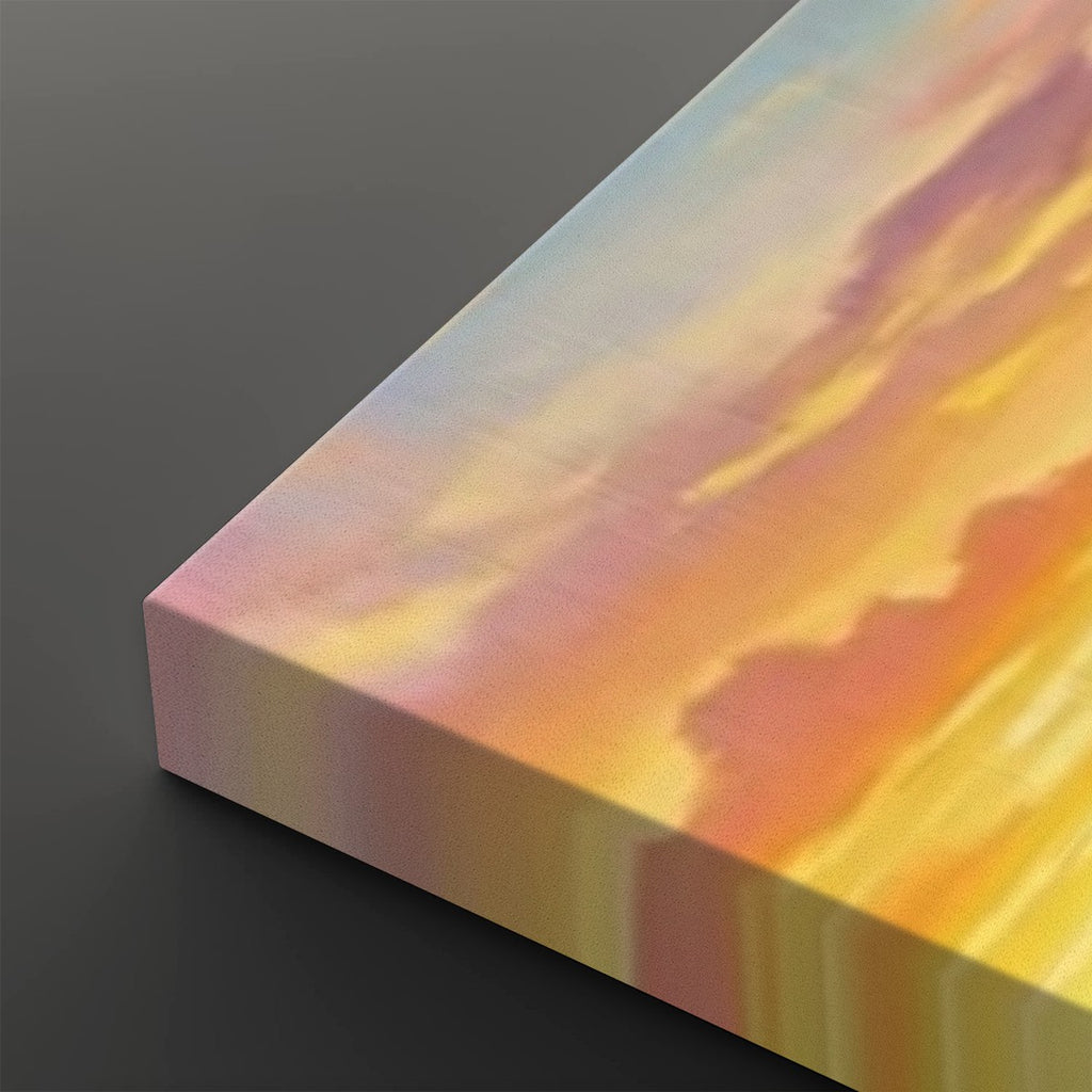 A close-up of a rectangular canvas or print showing an abstract sunset-like sky scene with blended yellow, orange, pink, and pale blue tones, photographed against a dark gray background.
