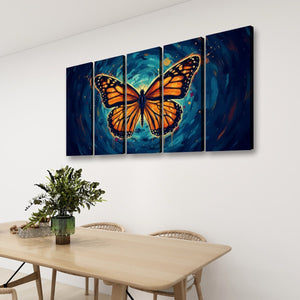 A four-panel canvas wall art set depicting a large orange monarch butterfly over a swirling blue and teal cosmic background, displayed on a white wall above a light wood dining table with chairs and a green plant.