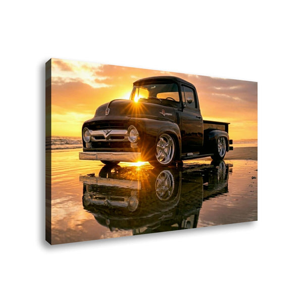 A rectangular wall art print or canvas showing a black  1956 Ford  F-100 vintage pickup truck parked on wet sand at sunset, with the truck reflected in the water. The print is photographed against a plain white background.