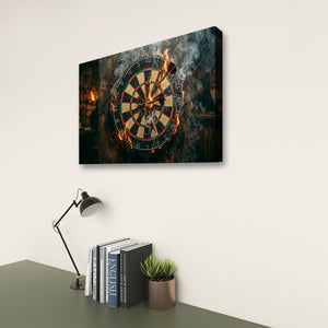 A rectangular wall art print showing a close-up of a dartboard with flaming darts, displayed on a light wall above a desk with books, a lamp, and a small plant.