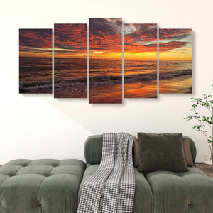 A 5-panel canvas wall art set depicting a dramatic Indian Rocks Beach, FL Sunset over the gulf, displayed on a white wall above a green tufted sofa.