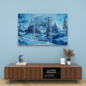 A three-panel canvas wall art set depicting a blue-toned winter landscape with snowy mountains, evergreen trees, and a river, displayed above a wooden media console against a light blue wall.