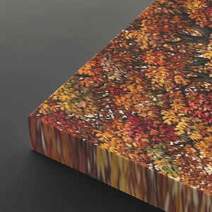 A close-up of a rectangular canvas or print showing an autumn tree canopy with dense orange, red, yellow, and brown leaves, photographed against a dark gray background.