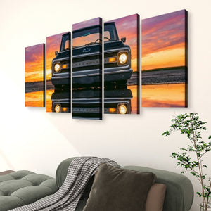 A 5-panel canvas wall art set depicting a black vintage 1970 Chevy C10 truck at sunset, displayed on a white wall above a green sofa in a living room setting.