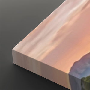 A close-up of a rectangular canvas or print showing a soft landscape scene with peach, pink, and blue tones, photographed on a dark gray background.