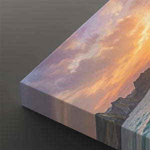 A close-up of a canvas wall art print showing a dramatic sunset sky with pink, orange, and purple clouds over dark rocky cliffs and a waterfall, photographed on a dark gray background.