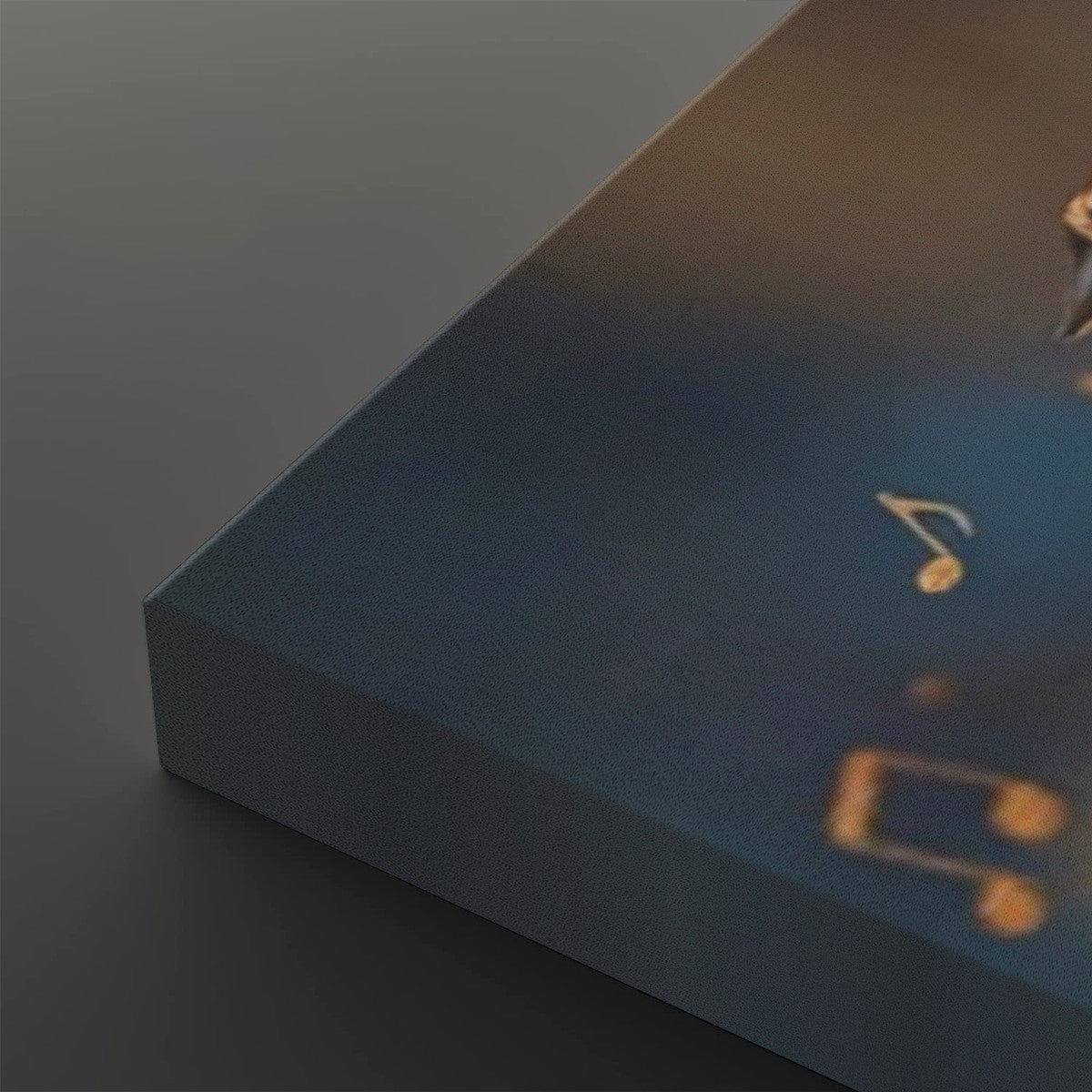 A close-up of a rectangular product, likely a book, box, or canvas, showing a dark blue textured surface with gold musical notes and a small gold emblem, photographed on a dark gray background.
