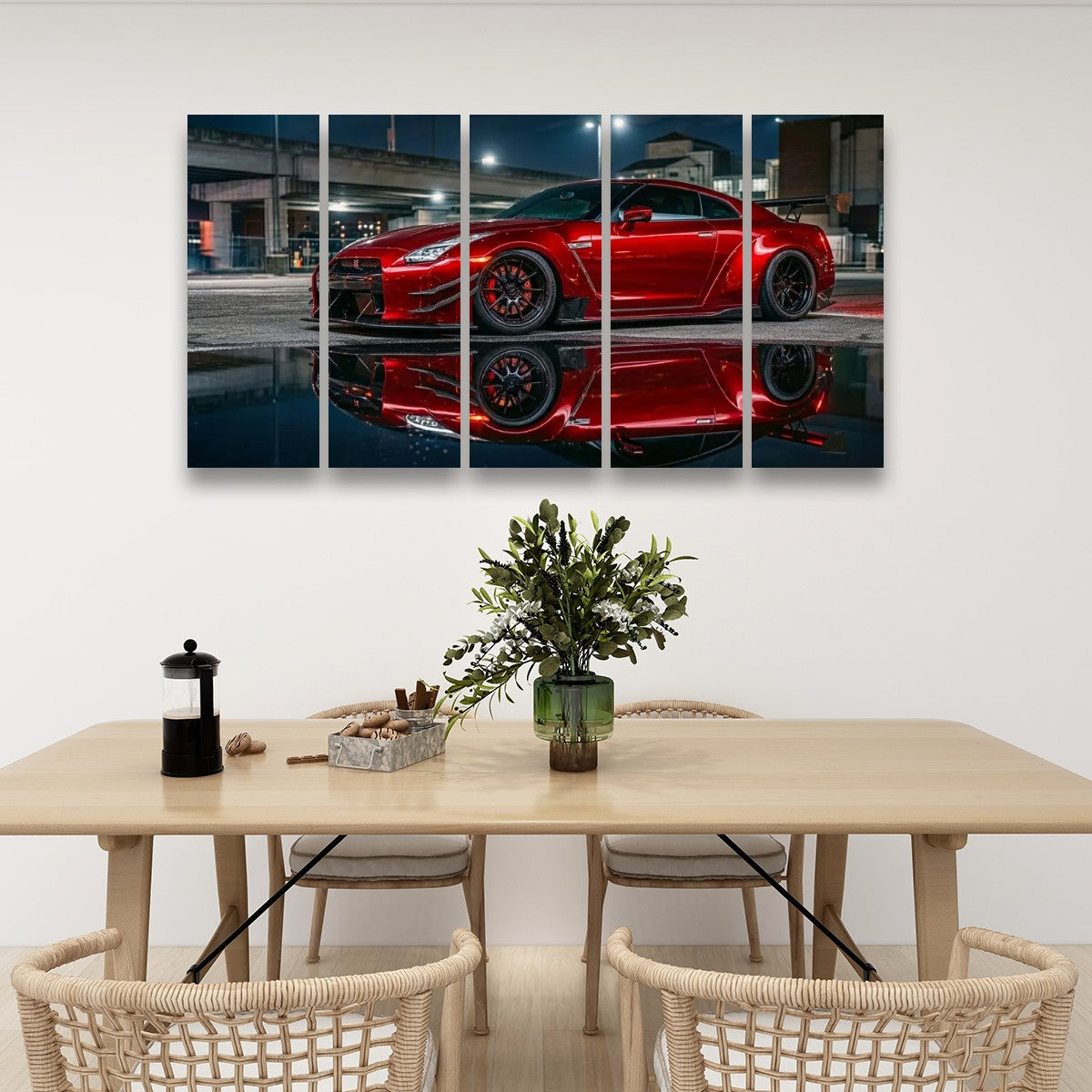 A 4-panel canvas wall art print depicting a red  Nissan GTR R35 sports car on a wet street at night with its reflection, displayed on a white wall above a dining table with chairs and a vase.