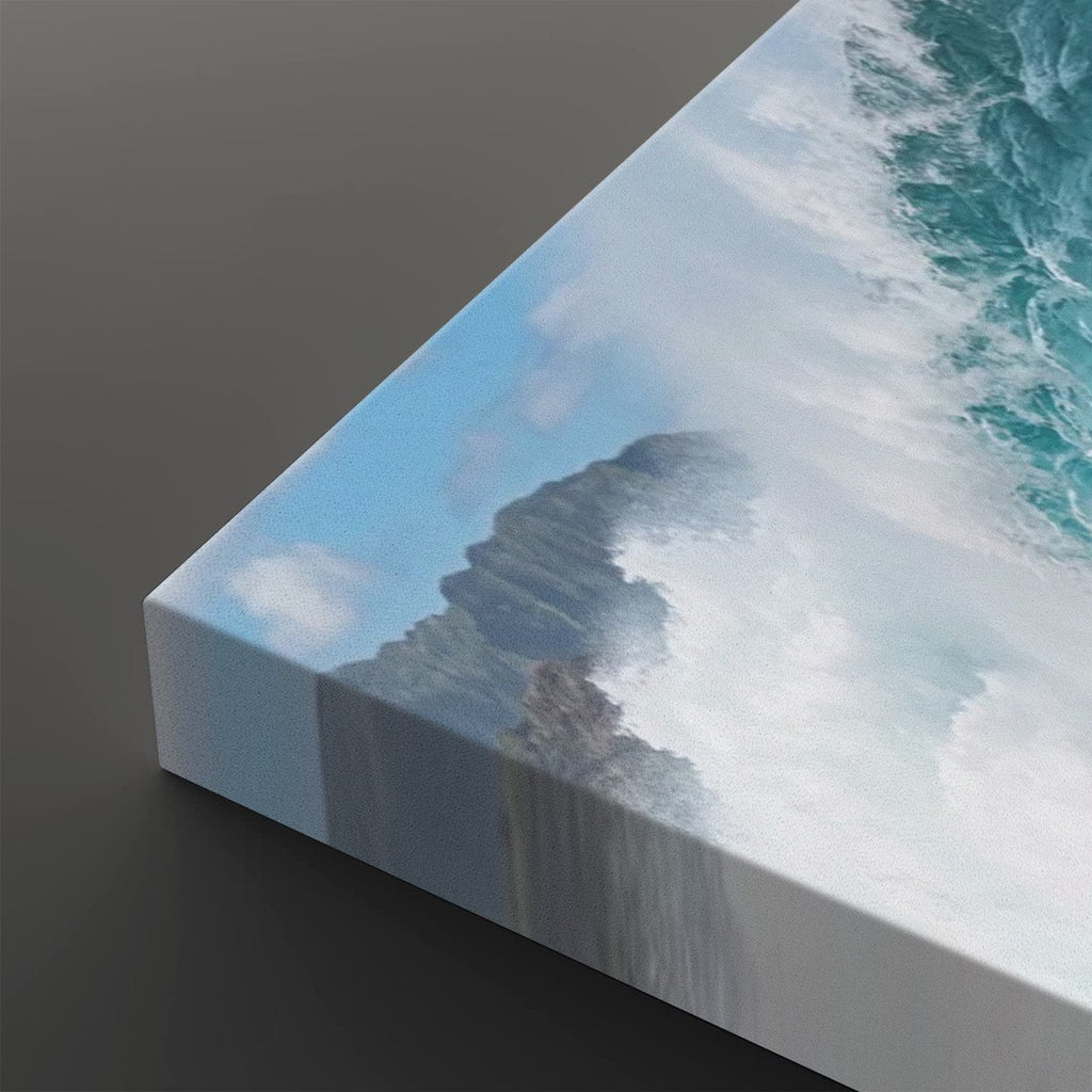 A close-up of a canvas wall art print showing a dramatic ocean wave crashing against a rocky shore, photographed at an angle on a dark gray background.