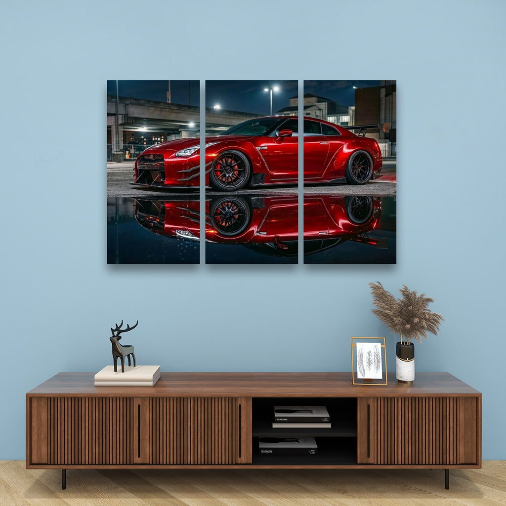A three-panel canvas wall art print depicting a red  Nissan GTR R35 sports car reflected in water, displayed on a light blue wall above a wooden console table with decorative items.