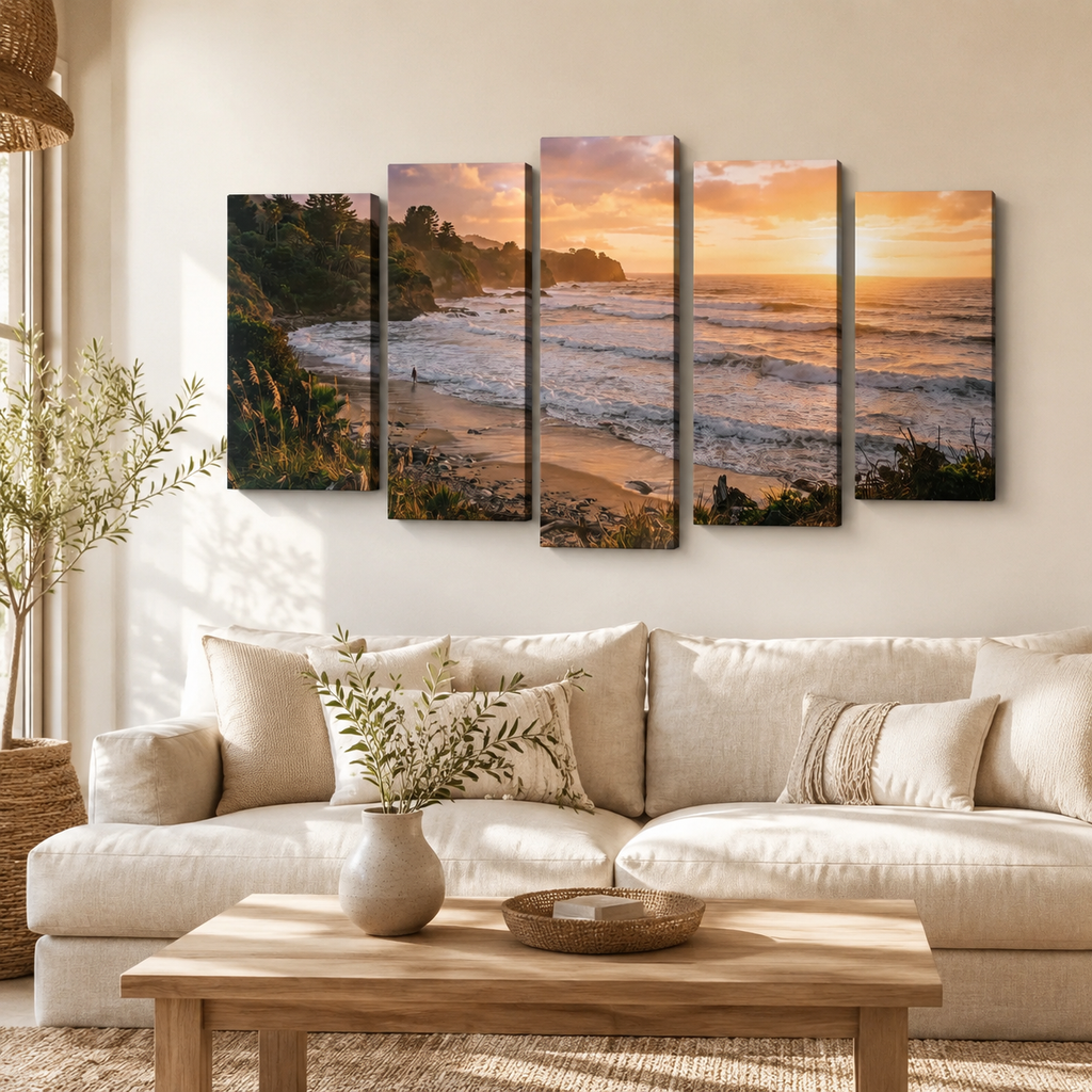 A 5-panel canvas wall art set depicting a coastal beach and ocean sunset, displayed on a beige wall above a modern beige sofa in a styled living room.