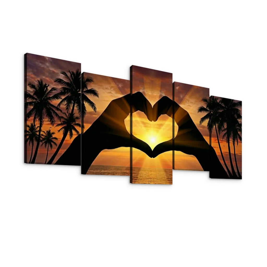 Five-panel canvas wall art showing a tropical sunset with palm tree silhouettes and hands forming a heart shape over the ocean, displayed against a white background.