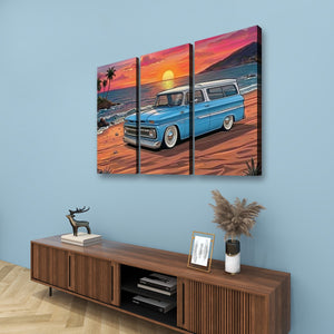 A three-panel canvas wall art set depicting a retro blue 1966 Chevy Suburban station wagon on a beach at sunset, displayed on a light blue wall above a wooden console table with decorative items.
