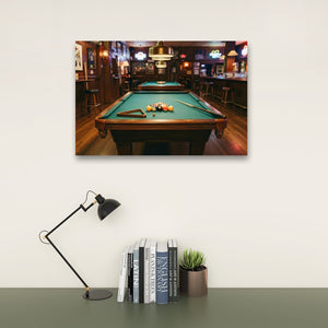 A framed wall art print showing a pool table in a dimly lit bar, displayed above a desk with a black desk lamp, books, and a small potted succulent on a light beige wall.