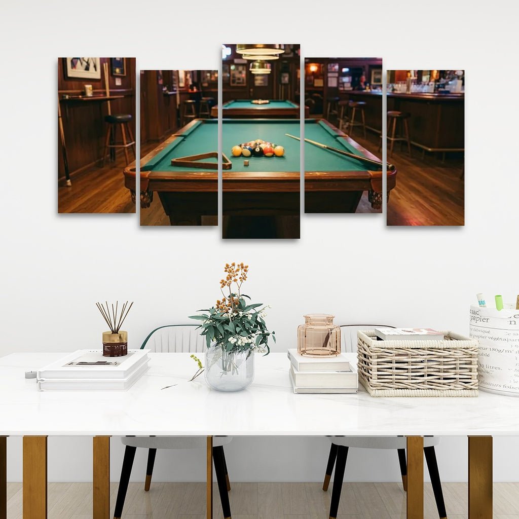 A 5-panel canvas wall art set depicting a pool table in a dimly lit bar, displayed on a white wall above a styled dining table with chairs and decorative items.