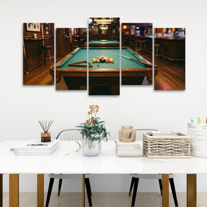 A 5-panel canvas wall art set depicting a pool table in a dimly lit bar, displayed on a white wall above a styled dining table with chairs and decorative items.