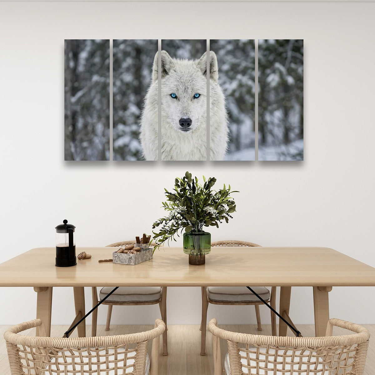 A five-panel canvas wall art set depicting a white wolf with blue eyes in a snowy forest, displayed above a light wood dining table with woven chairs in a modern dining room setting.