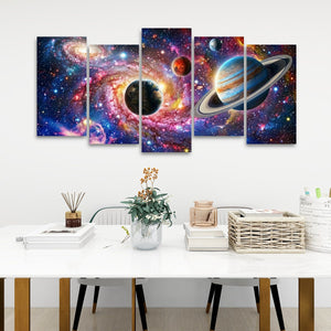 A five-panel canvas wall art set depicting a vibrant cosmic nebula with planets and stars, displayed on a white wall above a styled white table with books, a vase, and a basket.