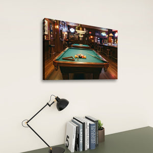 A rectangular wall art print showing a pool table in a dimly lit bar hangs on a light wall above a desk with a black lamp and books.