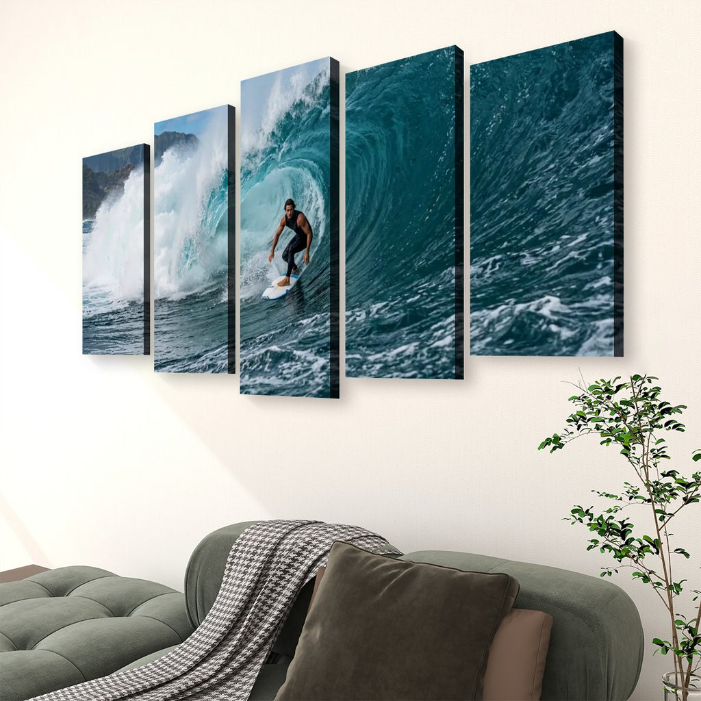 A five-panel canvas wall art set depicting a surfer riding a large blue ocean wave, displayed on a light beige wall above a green sofa with a throw blanket and a potted plant.