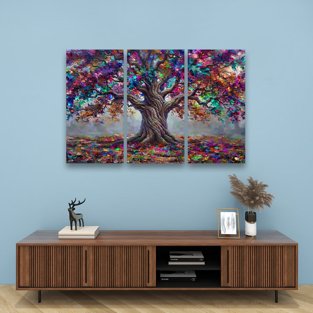 A three-panel canvas wall art set depicting a colorful, textured tree with vibrant autumn foliage, displayed on a light blue wall above a wooden console table with decorative items.