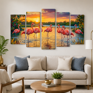 A 5-panel canvas wall art set depicting pink flamingos at sunset over a lake, displayed on a beige wall above a modern white sofa in a living room setting.